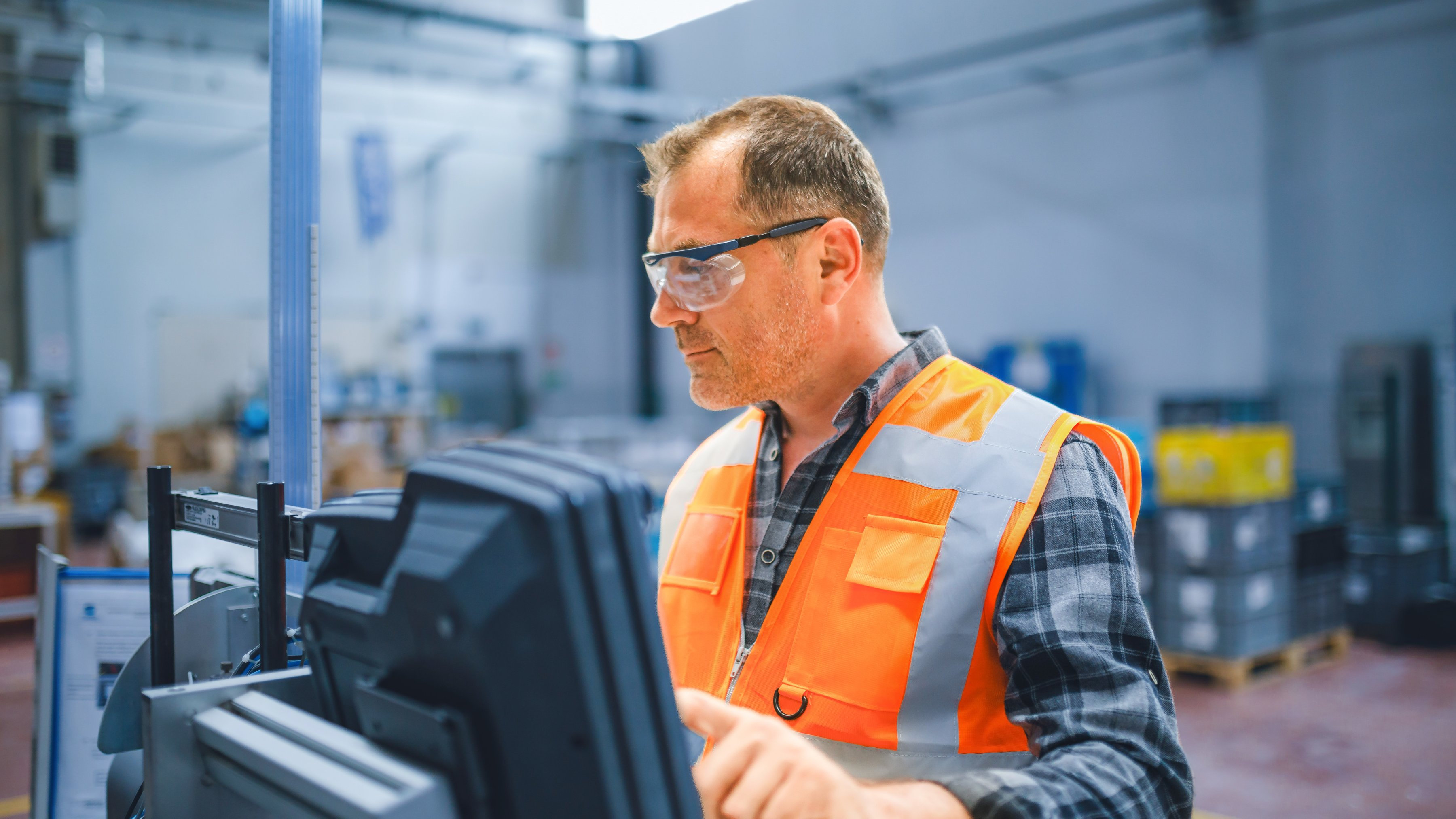 An industrial worker is using equipment in a factory.