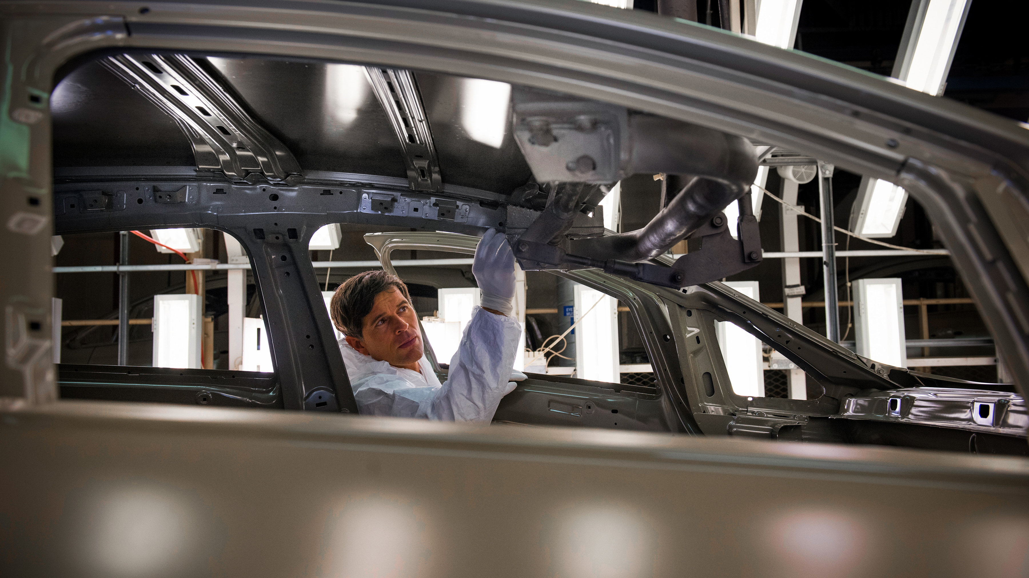 Manufacturing worker inspecting a car on the production line.